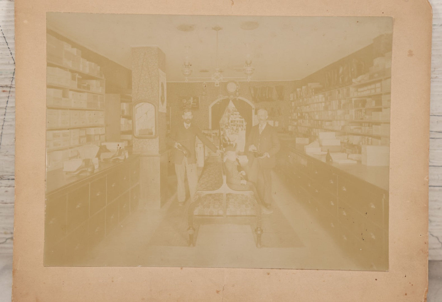 Lot 076 - Antique Boarded Photograph Of Three Men And Young Boy In Boot And Shoe Store, With Products And Advertising Visible In Photo