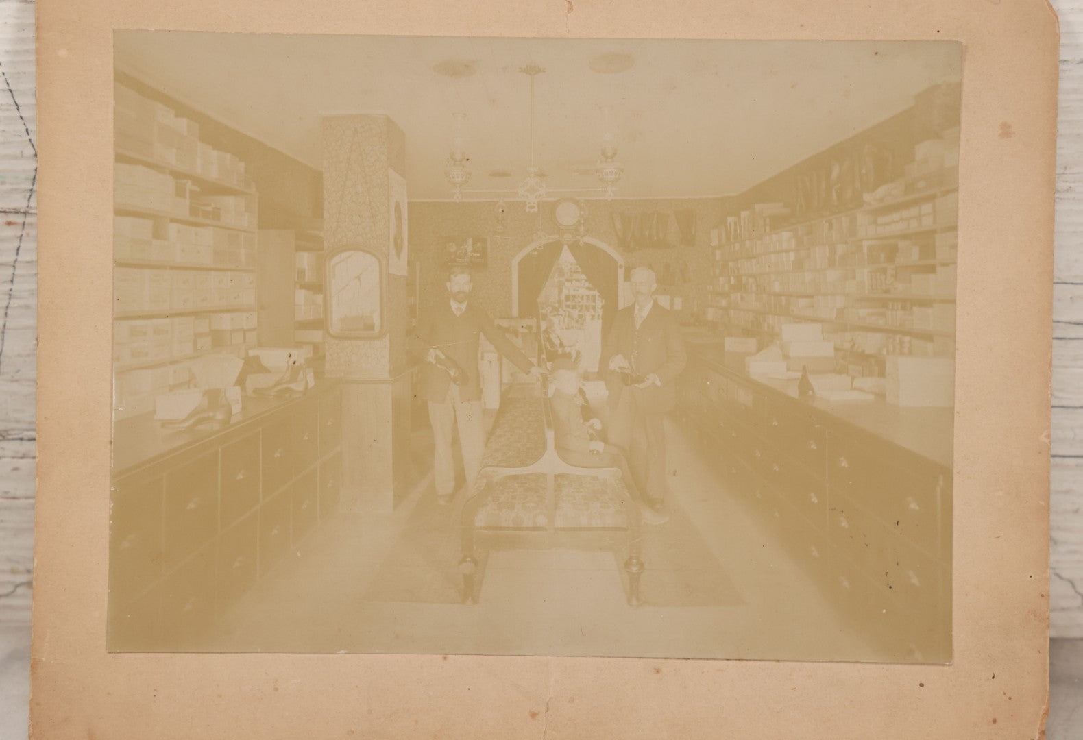 Lot 076 - Antique Boarded Photograph Of Three Men And Young Boy In Boot And Shoe Store, With Products And Advertising Visible In Photo