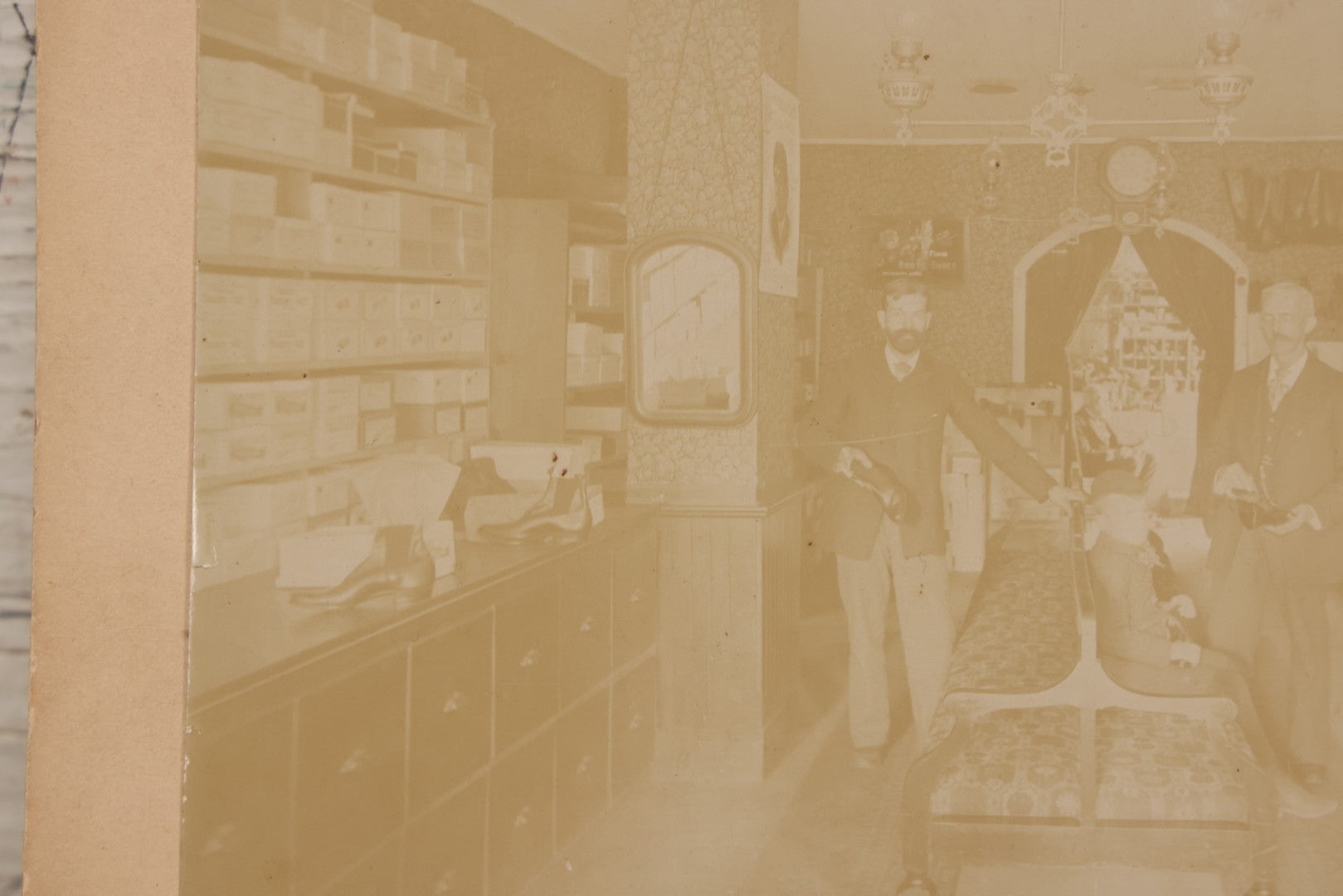 Lot 076 - Antique Boarded Photograph Of Three Men And Young Boy In Boot And Shoe Store, With Products And Advertising Visible In Photo