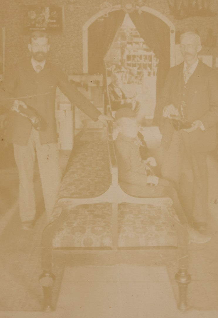 Lot 076 - Antique Boarded Photograph Of Three Men And Young Boy In Boot And Shoe Store, With Products And Advertising Visible In Photo