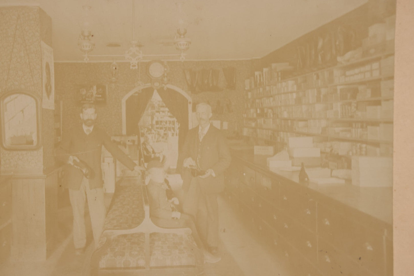 Lot 076 - Antique Boarded Photograph Of Three Men And Young Boy In Boot And Shoe Store, With Products And Advertising Visible In Photo