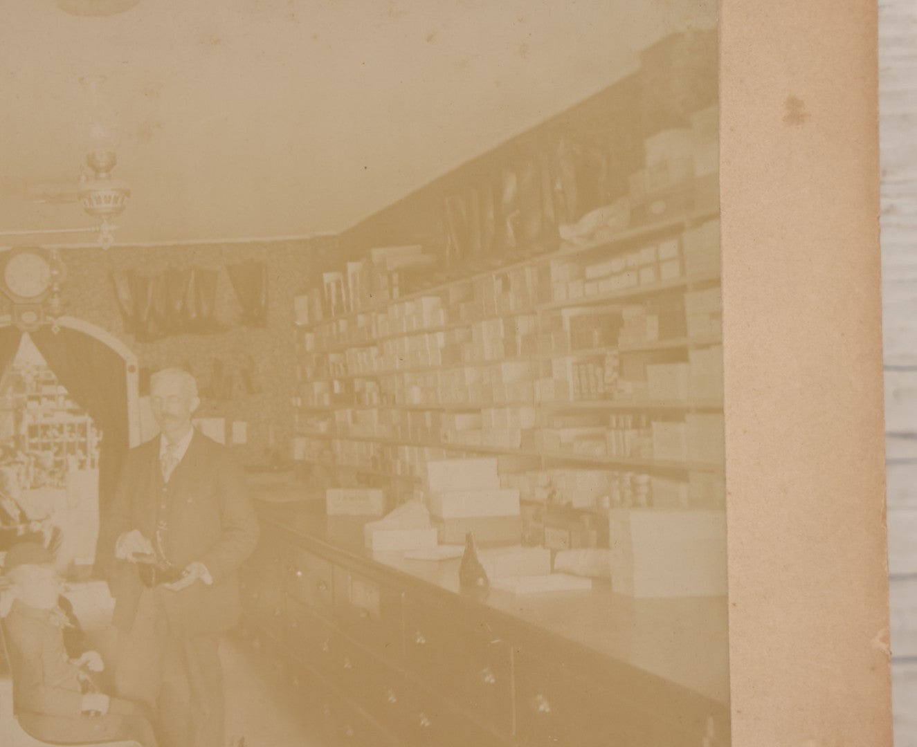 Lot 076 - Antique Boarded Photograph Of Three Men And Young Boy In Boot And Shoe Store, With Products And Advertising Visible In Photo