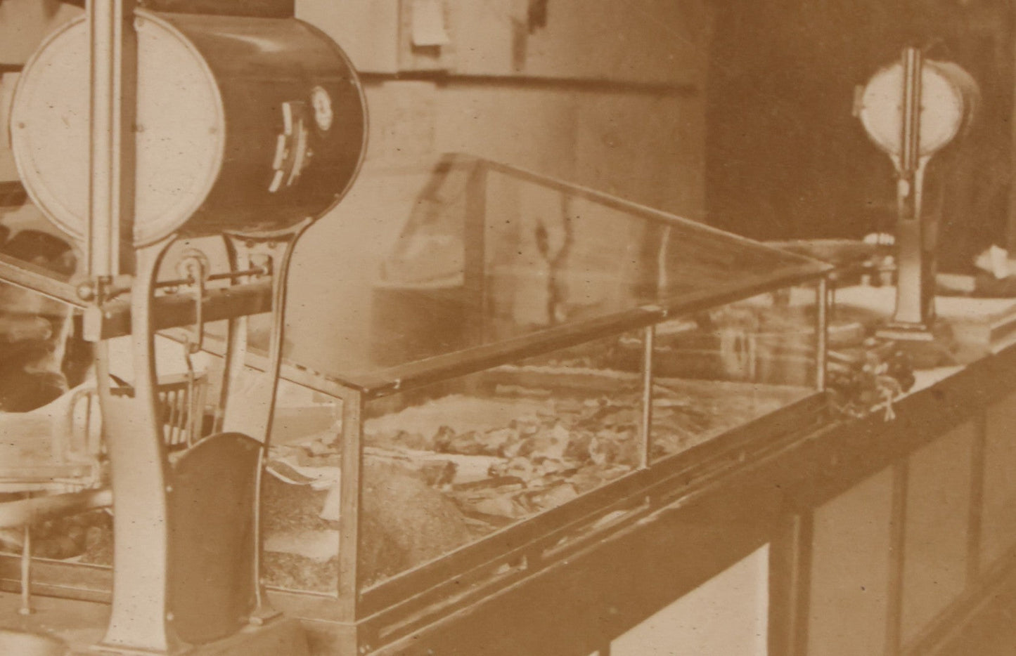 Lot 077 - Antique Boarded Occupational Photograph Of Two Butchers Behind Counter, With Sausage, Full Pig, And Other Meat Products Visible In Photo, And Large Commercial Scale