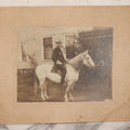 Lot 083 - Antique Boarded Photograph Of Man In Uniform Sitting Horseback On White Horse With Saddle Blanket Emblazoned With Star, Western Hat And Badge