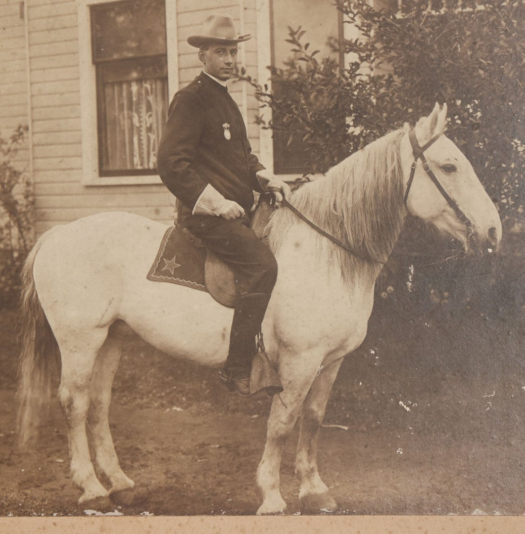Lot 083 - Antique Boarded Photograph Of Man In Uniform Sitting Horseback On White Horse With Saddle Blanket Emblazoned With Star, Western Hat And Badge