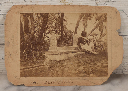 Lot 100 - Antique Boarded Photograph Of Person Sitting At Gravesite Identified As "An Arab Tomb", Partial Photographer Mark And Monogram On Photo Board, Out Of Algeria, Note Losses And Cracking Throughout Photo And Board, Poor Condition