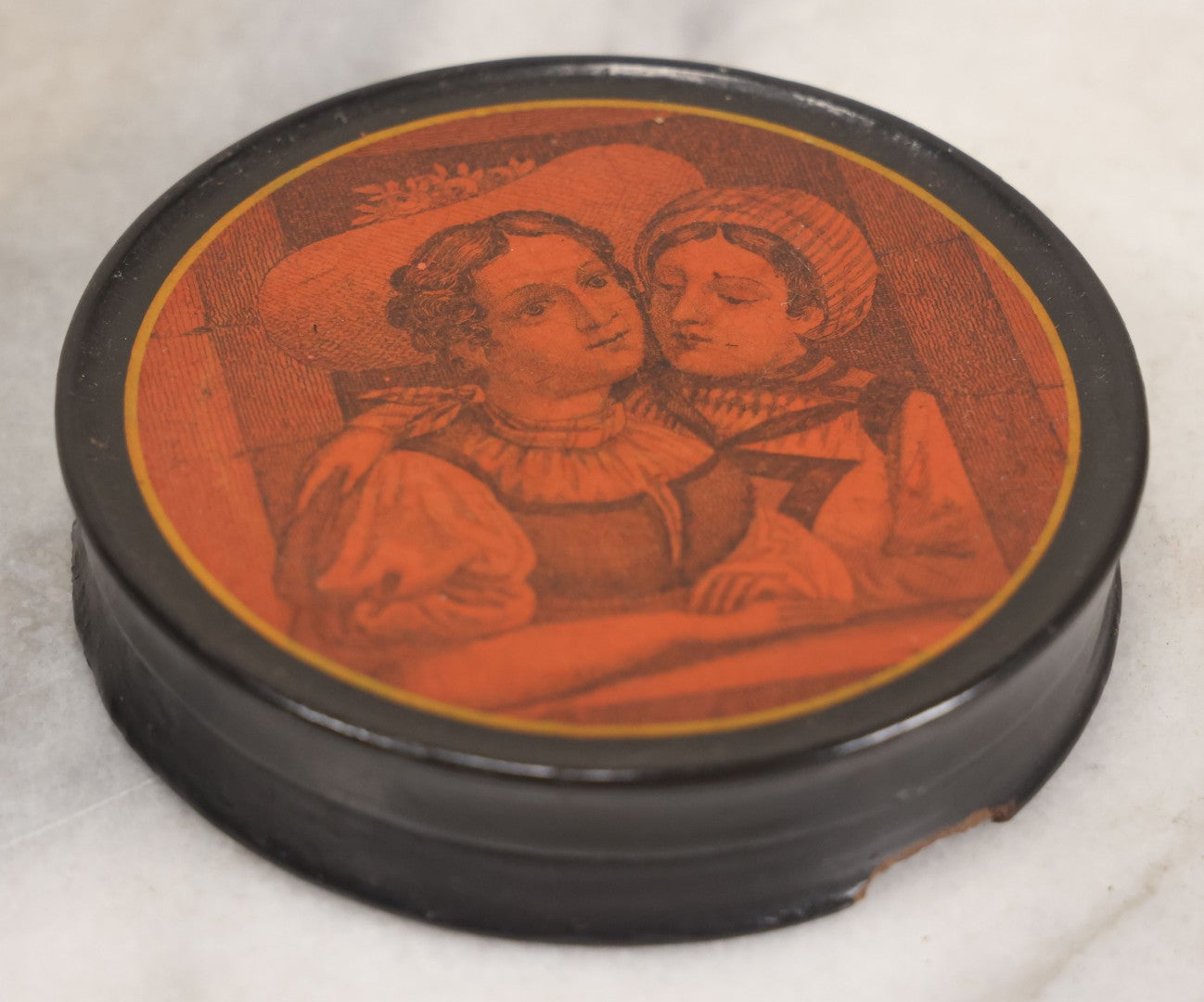 Lot 011 - Antique Laquered Papier Mache Dresser Box With Lithographed Lid Of One Woman Comforting Another, Note Small Loss To Bottom Lip