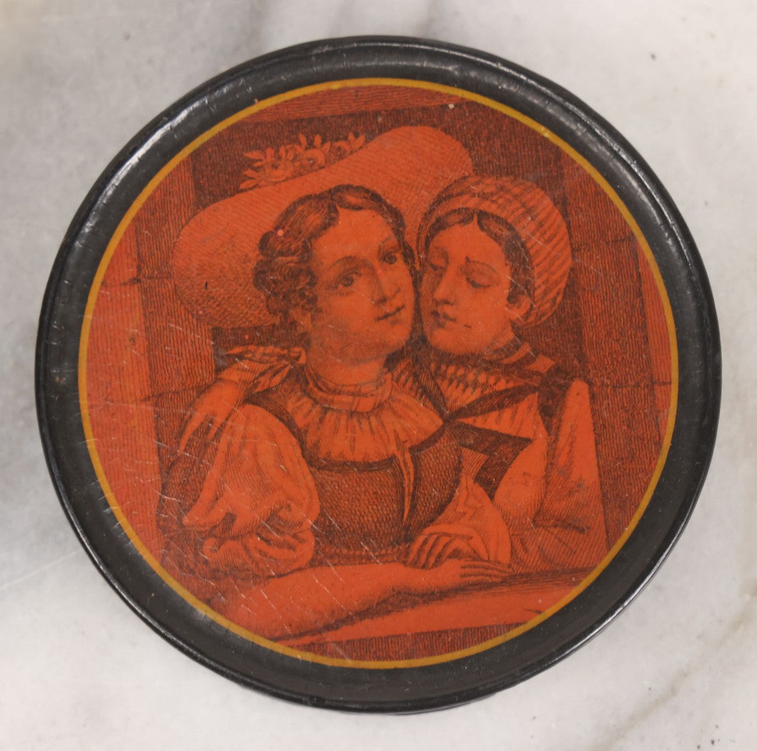 Lot 011 - Antique Laquered Papier Mache Dresser Box With Lithographed Lid Of One Woman Comforting Another, Note Small Loss To Bottom Lip