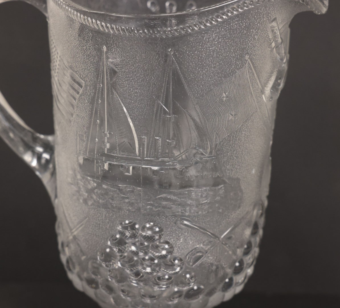 Lot 027 - Antique Early American Pattern Glass E.A.P.G. Spanish American War Battle Of Manila Bay Commemorative Pitcher With Admiral Dewey And U.S.S. Olympia, Patriotic Symbols Including Weaponry And Flags, Manufactured By Beatty-Brady Glass Co., Indiana