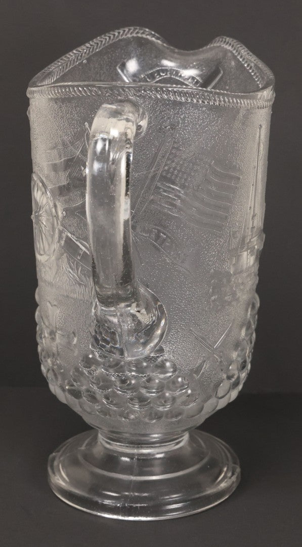Lot 027 - Antique Early American Pattern Glass E.A.P.G. Spanish American War Battle Of Manila Bay Commemorative Pitcher With Admiral Dewey And U.S.S. Olympia, Patriotic Symbols Including Weaponry And Flags, Manufactured By Beatty-Brady Glass Co., Indiana