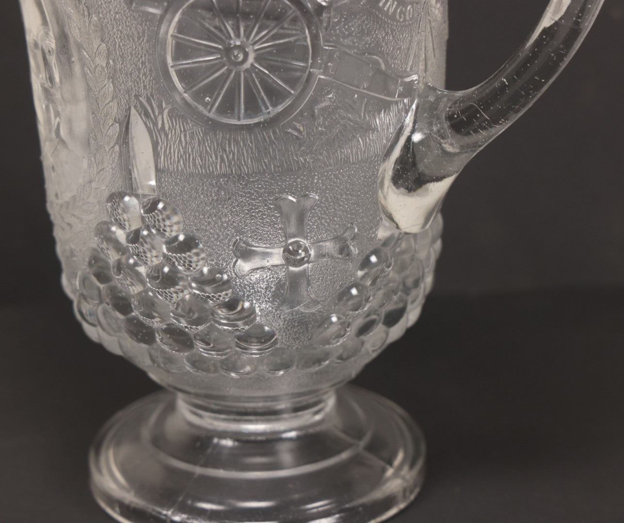 Lot 027 - Antique Early American Pattern Glass E.A.P.G. Spanish American War Battle Of Manila Bay Commemorative Pitcher With Admiral Dewey And U.S.S. Olympia, Patriotic Symbols Including Weaponry And Flags, Manufactured By Beatty-Brady Glass Co., Indiana