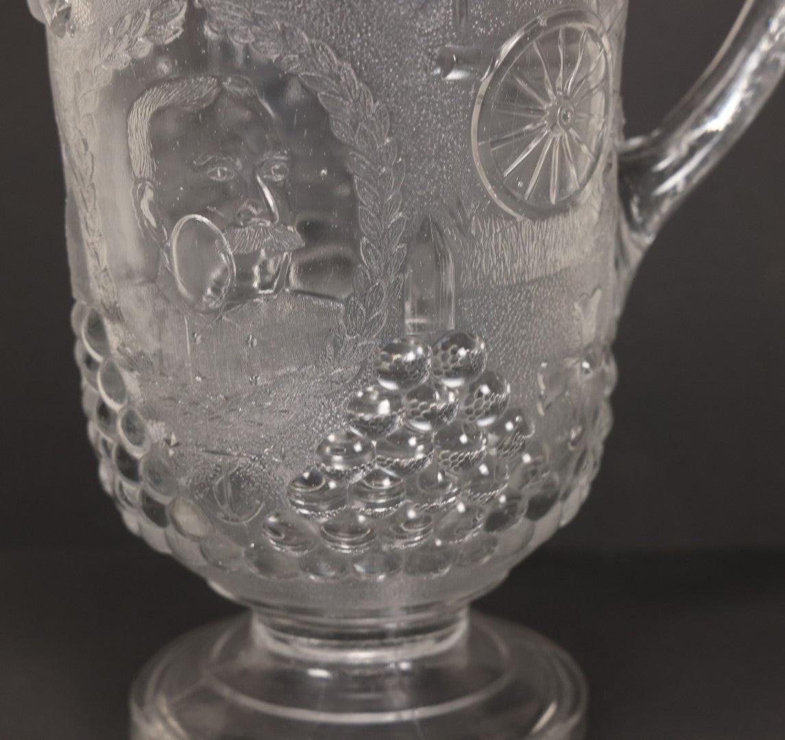 Lot 027 - Antique Early American Pattern Glass E.A.P.G. Spanish American War Battle Of Manila Bay Commemorative Pitcher With Admiral Dewey And U.S.S. Olympia, Patriotic Symbols Including Weaponry And Flags, Manufactured By Beatty-Brady Glass Co., Indiana