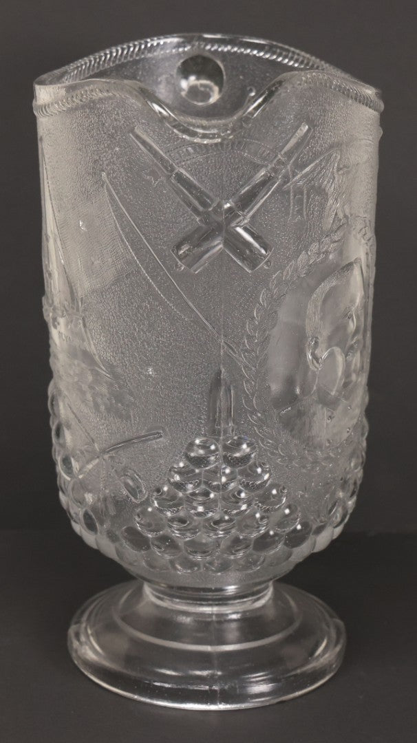 Lot 027 - Antique Early American Pattern Glass E.A.P.G. Spanish American War Battle Of Manila Bay Commemorative Pitcher With Admiral Dewey And U.S.S. Olympia, Patriotic Symbols Including Weaponry And Flags, Manufactured By Beatty-Brady Glass Co., Indiana