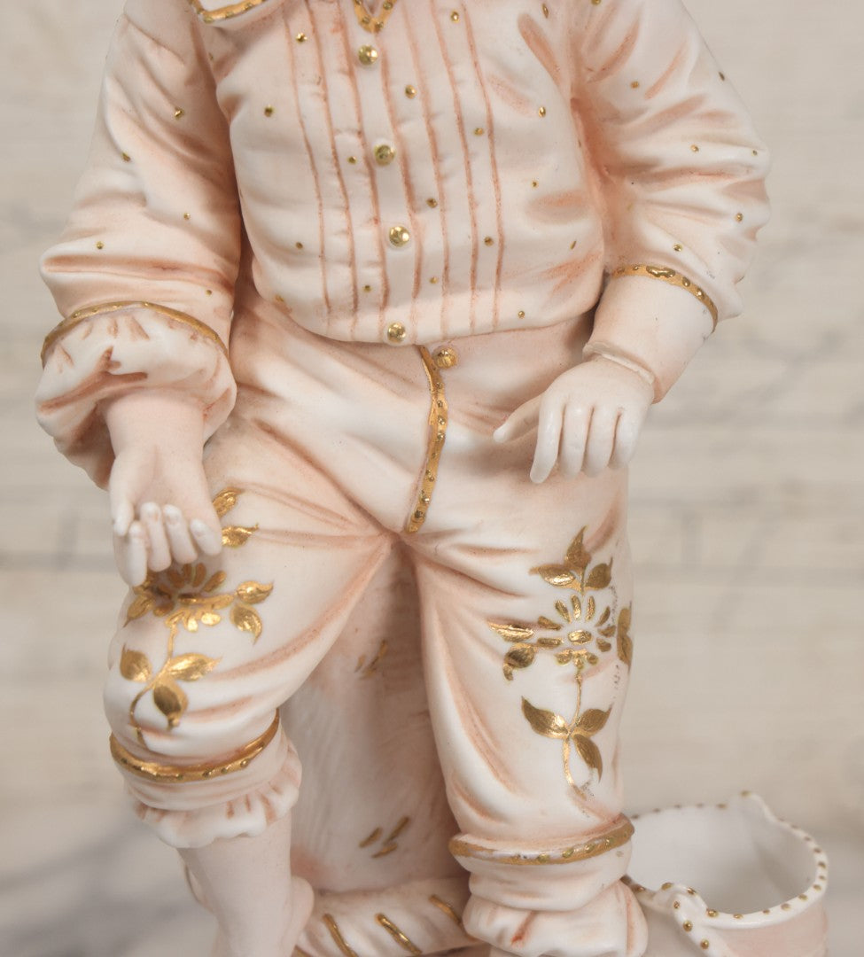 Lot 037 - Vintage Bisque Statue Of Young Blond Child In Large Straw Hat Sitting By Shore With Pail, With Pink Painted Details And Gold Embellishments, Note Chip, Repairs, 12" Height