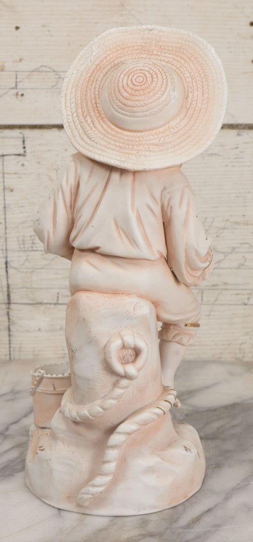 Lot 037 - Vintage Bisque Statue Of Young Blond Child In Large Straw Hat Sitting By Shore With Pail, With Pink Painted Details And Gold Embellishments, Note Chip, Repairs, 12" Height