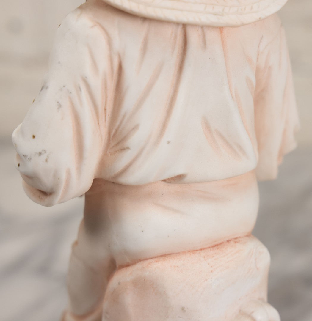 Lot 037 - Vintage Bisque Statue Of Young Blond Child In Large Straw Hat Sitting By Shore With Pail, With Pink Painted Details And Gold Embellishments, Note Chip, Repairs, 12" Height