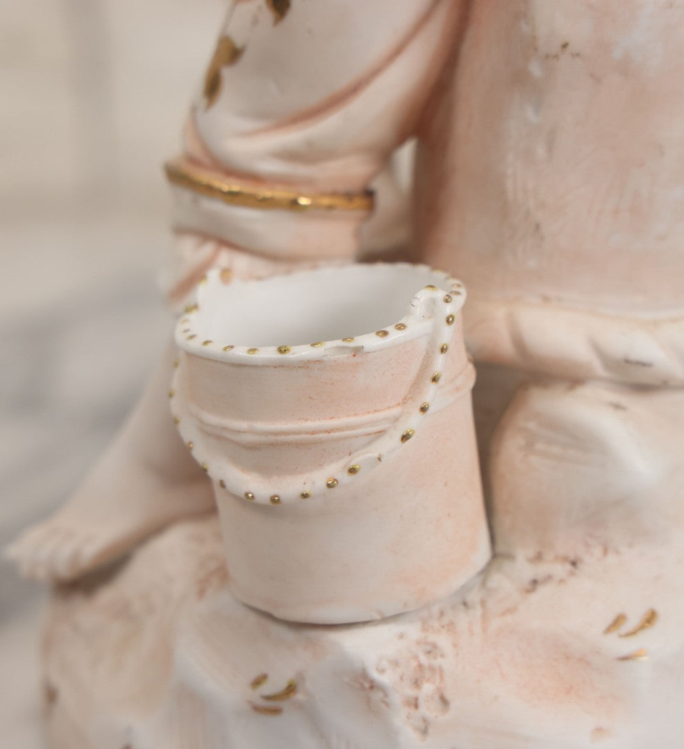 Lot 037 - Vintage Bisque Statue Of Young Blond Child In Large Straw Hat Sitting By Shore With Pail, With Pink Painted Details And Gold Embellishments, Note Chip, Repairs, 12" Height