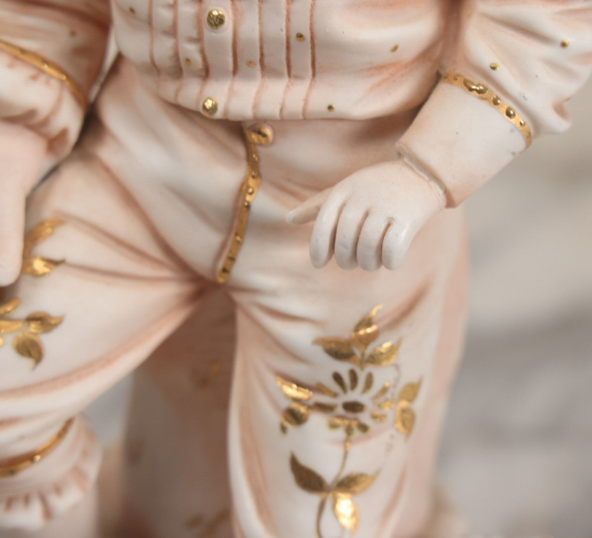 Lot 037 - Vintage Bisque Statue Of Young Blond Child In Large Straw Hat Sitting By Shore With Pail, With Pink Painted Details And Gold Embellishments, Note Chip, Repairs, 12" Height