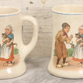 Lot 040 - Pair Of Antique Mugs With Image Of Dutch Children In Clogs Playing With Their Kitten, Windmill In Background