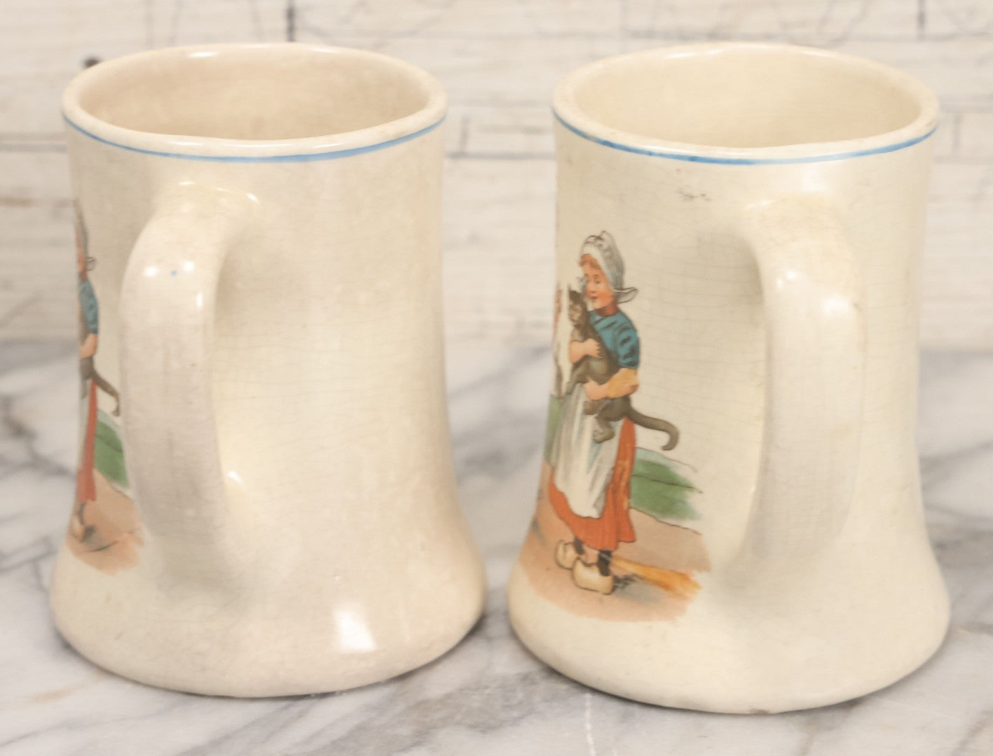 Lot 040 - Pair Of Antique Mugs With Image Of Dutch Children In Clogs Playing With Their Kitten, Windmill In Background