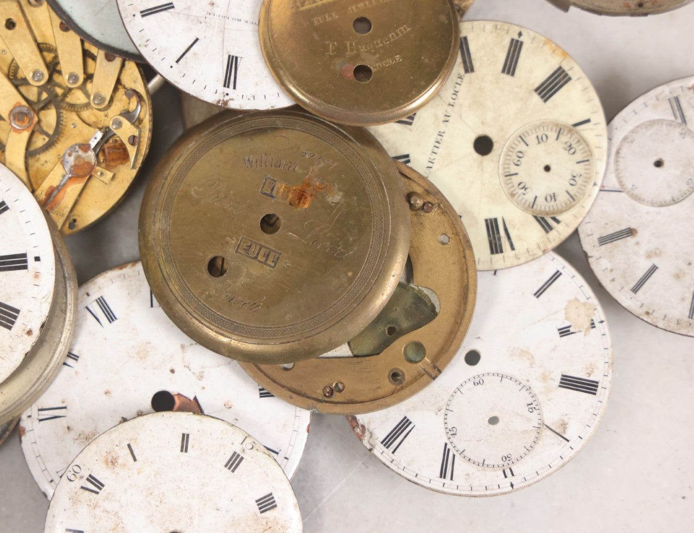 Lot 048 - Mixed Antique Salvage Grouping Of Pocket Watch Parts Including Porcelein Clock Faces, Movements, And Case Parts, 35+ Pieces, Makers Include J.F. Cooper, William Favre, F. Huquenm, M.J. Tobias
