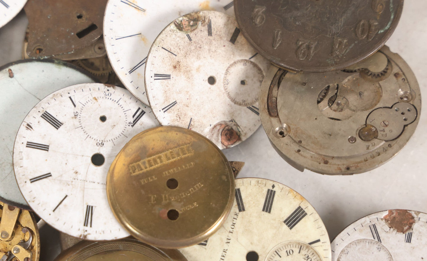 Lot 048 - Mixed Antique Salvage Grouping Of Pocket Watch Parts Including Porcelein Clock Faces, Movements, And Case Parts, 35+ Pieces, Makers Include J.F. Cooper, William Favre, F. Huquenm, M.J. Tobias