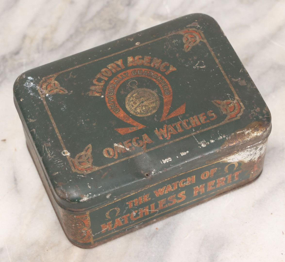 Lot 049 - Vintage Tin Lithograph Factory Agency Advertising Tin For Omega Watches, "The Watch Of Matchless Merit; Universally Guarenteed" 