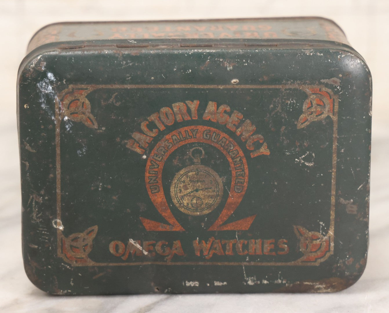 Lot 049 - Vintage Tin Lithograph Factory Agency Advertising Tin For Omega Watches, "The Watch Of Matchless Merit; Universally Guarenteed" 