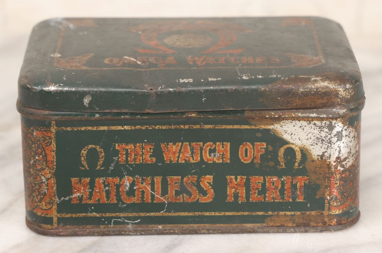 Lot 049 - Vintage Tin Lithograph Factory Agency Advertising Tin For Omega Watches, "The Watch Of Matchless Merit; Universally Guarenteed" 