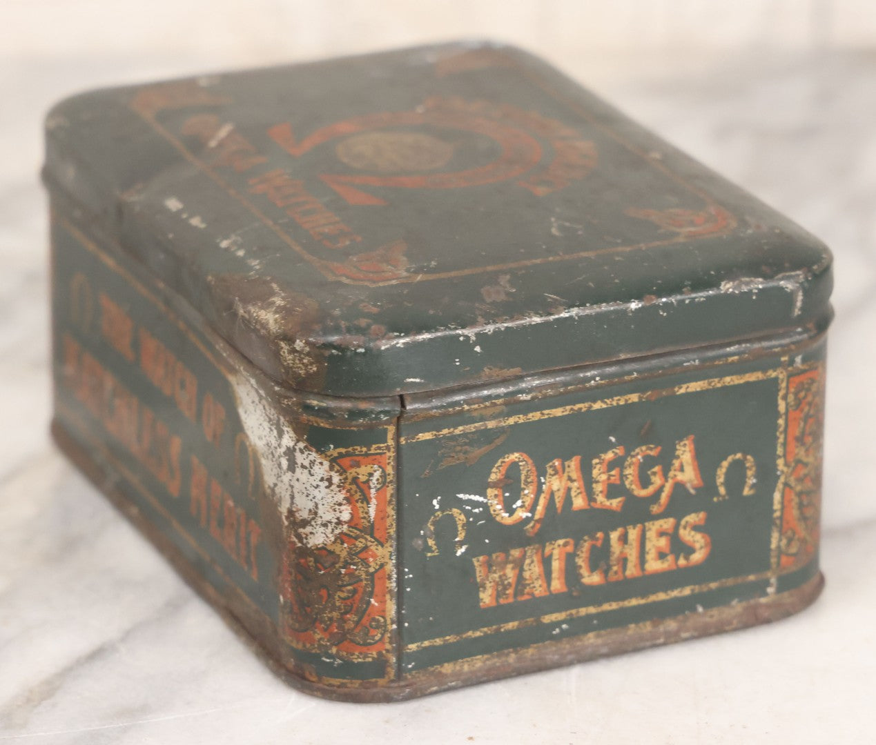 Lot 049 - Vintage Tin Lithograph Factory Agency Advertising Tin For Omega Watches, "The Watch Of Matchless Merit; Universally Guarenteed" 