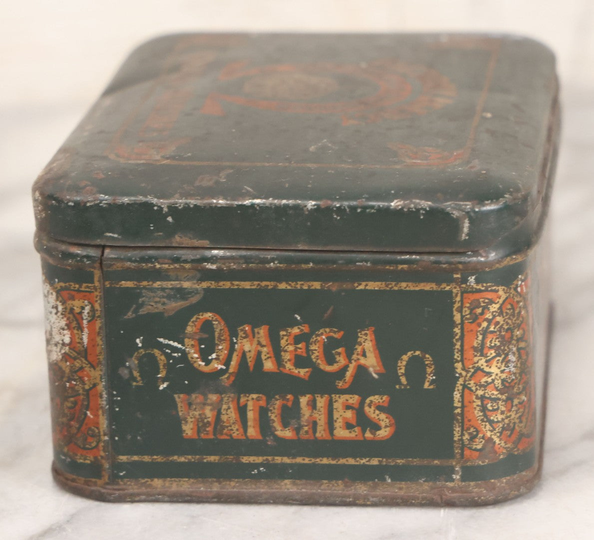 Lot 049 - Vintage Tin Lithograph Factory Agency Advertising Tin For Omega Watches, "The Watch Of Matchless Merit; Universally Guarenteed" 