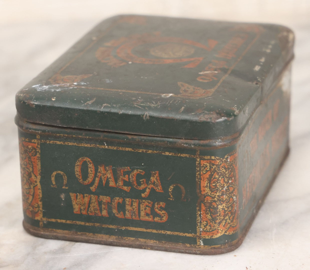 Lot 049 - Vintage Tin Lithograph Factory Agency Advertising Tin For Omega Watches, "The Watch Of Matchless Merit; Universally Guarenteed" 