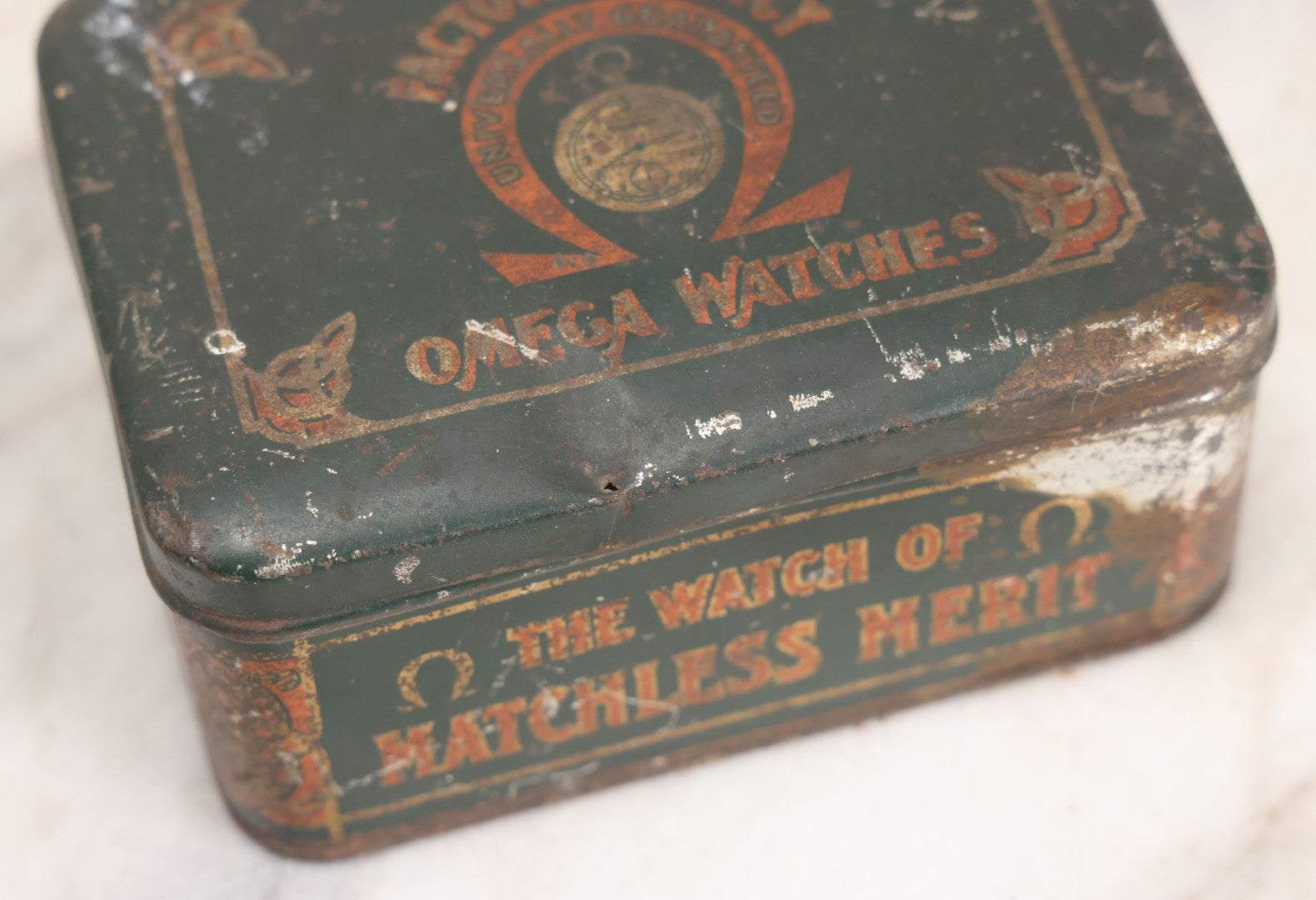 Lot 049 - Vintage Tin Lithograph Factory Agency Advertising Tin For Omega Watches, "The Watch Of Matchless Merit; Universally Guarenteed" 