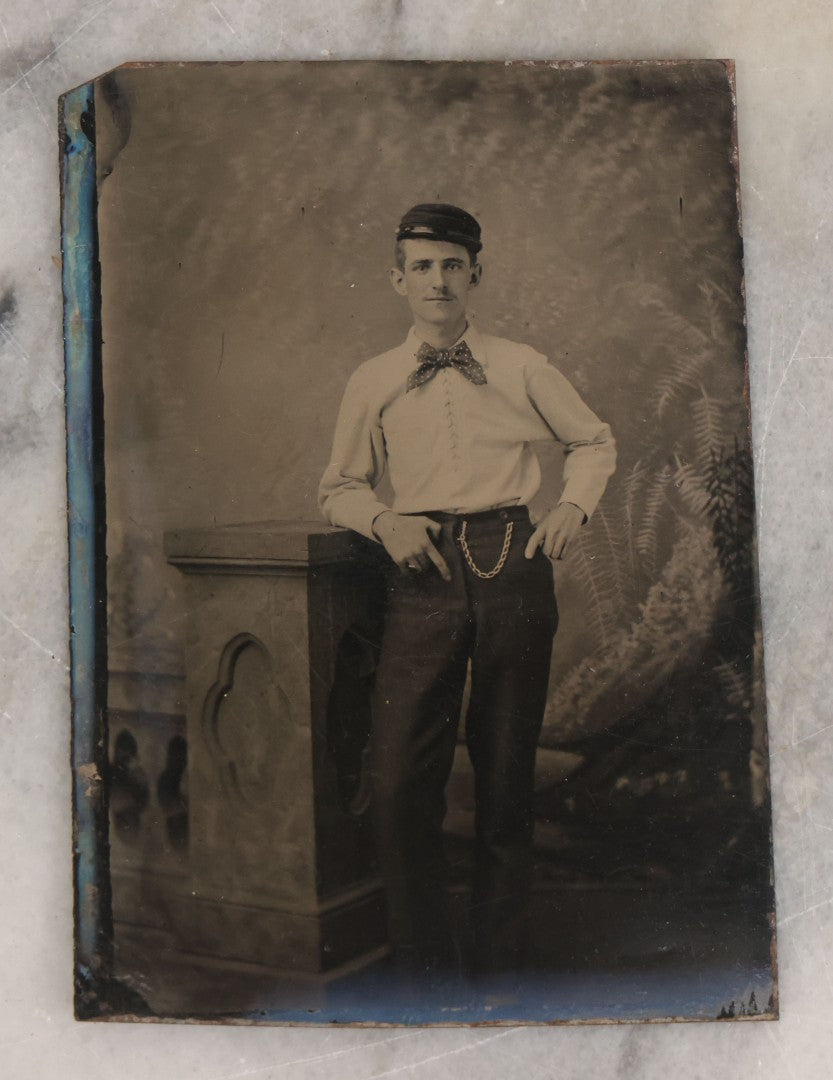 Lot 073 - Single Antique Tintype Photograph Of Well-Dressed Fella Wearing White Shirt, Polka Dot Bowtie, Cap, And Watch Chain, With A Cool Pose