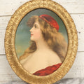 Lot 006 - Antique Chromolithograph Portrait Print Of Blue-Eyed Brunette Beauty With Red Velvet Cap And Loose Fitting Red Gown In Ornate Gilded Molded Gesso Oval Frame, 21" x 25"