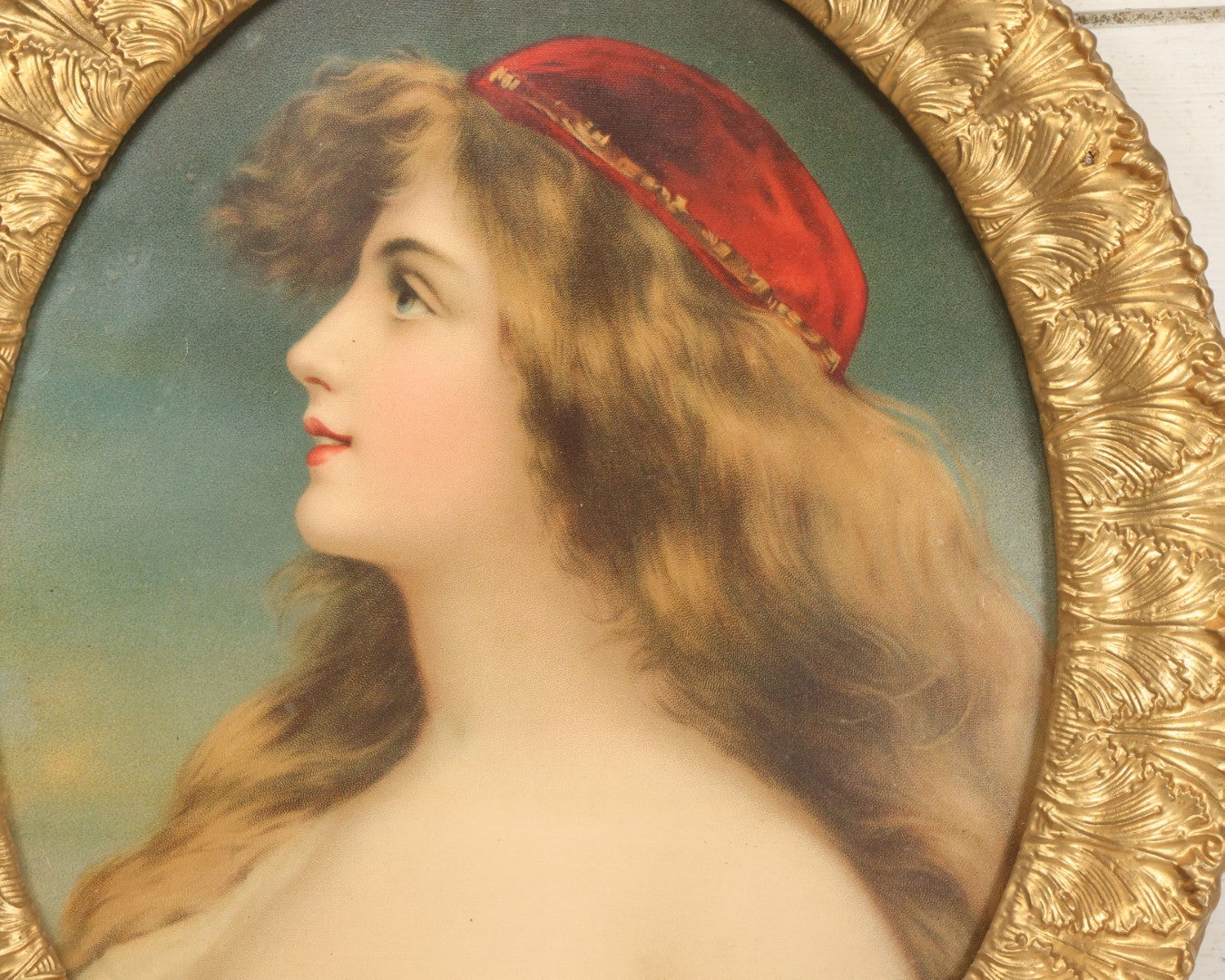 Lot 006 - Antique Chromolithograph Portrait Print Of Blue-Eyed Brunette Beauty With Red Velvet Cap And Loose Fitting Red Gown In Ornate Gilded Molded Gesso Oval Frame, 21" x 25"