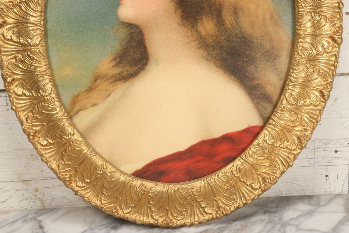 Lot 006 - Antique Chromolithograph Portrait Print Of Blue-Eyed Brunette Beauty With Red Velvet Cap And Loose Fitting Red Gown In Ornate Gilded Molded Gesso Oval Frame, 21" x 25"