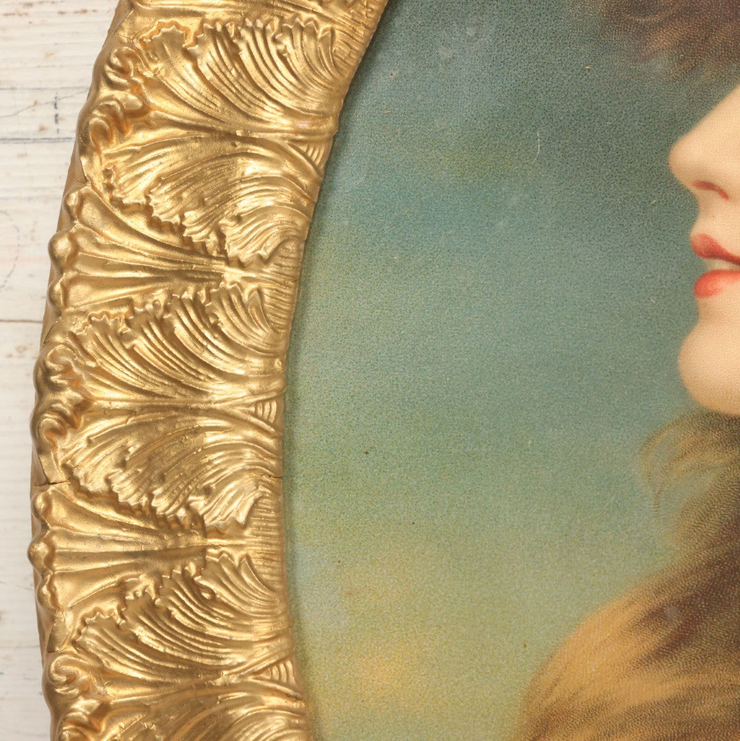 Lot 006 - Antique Chromolithograph Portrait Print Of Blue-Eyed Brunette Beauty With Red Velvet Cap And Loose Fitting Red Gown In Ornate Gilded Molded Gesso Oval Frame, 21" x 25"