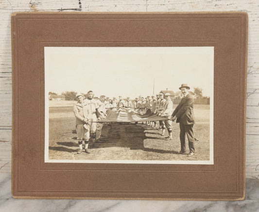 Lot 139 - Antique Boarded Photograph Of The Players Of A Baseball Team In Uniform Posing With A Large Flag, Uniforms Say "Royal League" With Patches Visible