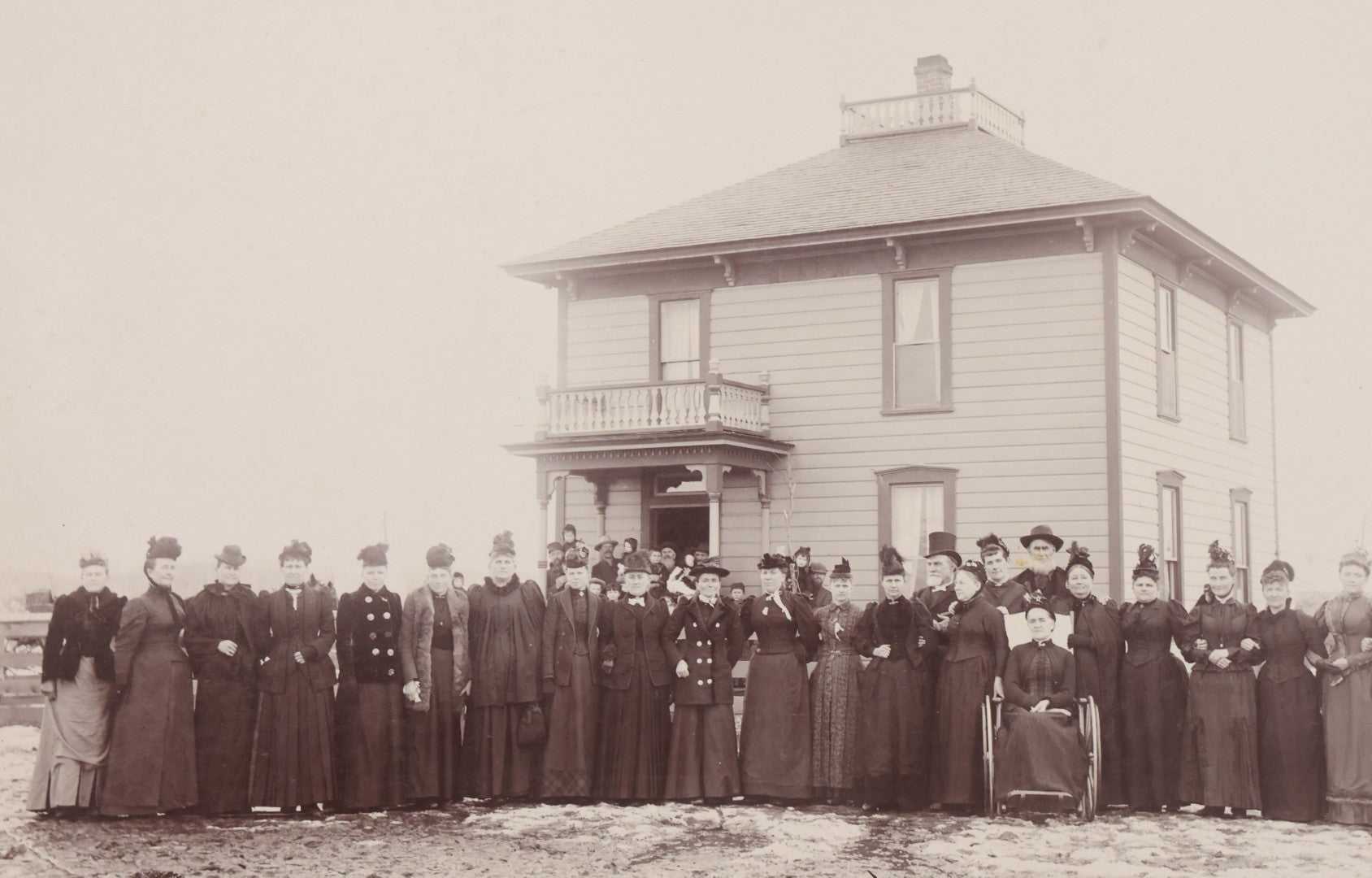 Lot 140 - Antique Boarded Photograph Of Group Of Women In Dark Attire Posing Outside Two Story Home, Including Men In Top Hats And Woman In Wheelchair, Photographed By U.H. Henry, Prescott, Washington