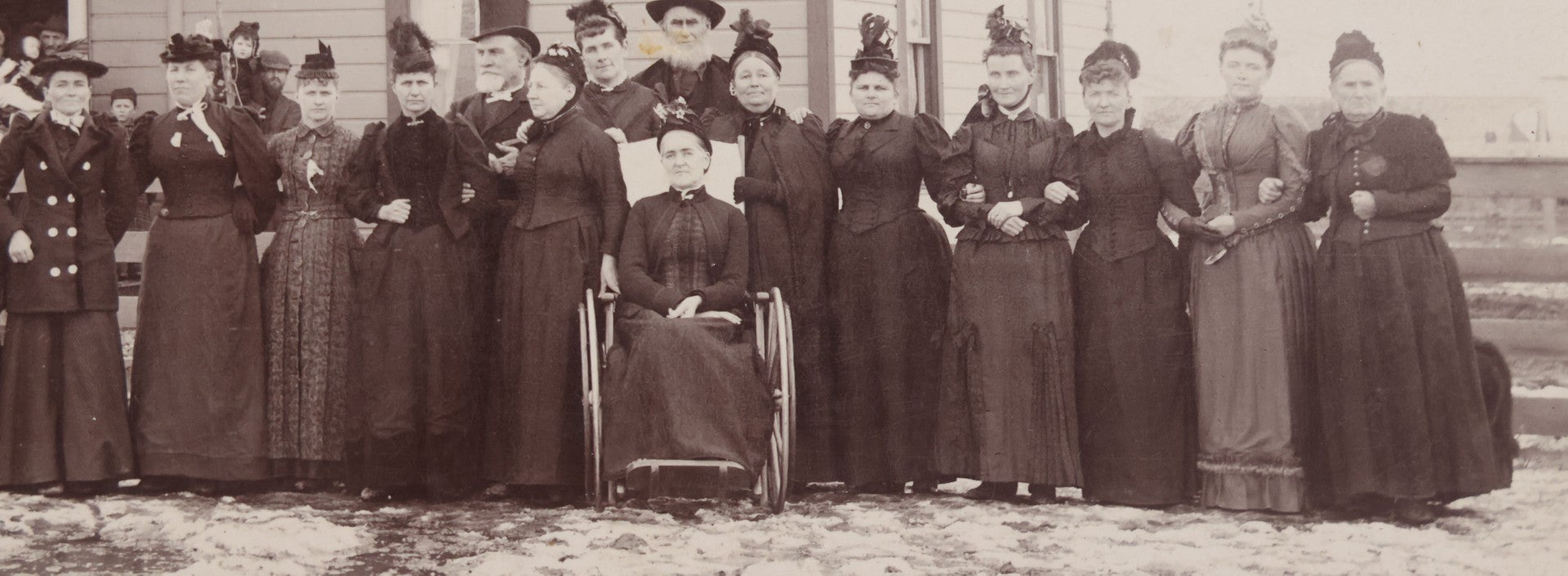Lot 140 - Antique Boarded Photograph Of Group Of Women In Dark Attire Posing Outside Two Story Home, Including Men In Top Hats And Woman In Wheelchair, Photographed By U.H. Henry, Prescott, Washington