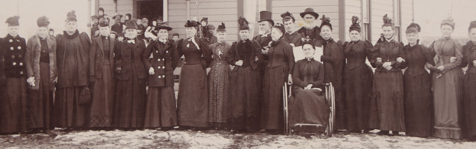 Lot 140 - Antique Boarded Photograph Of Group Of Women In Dark Attire Posing Outside Two Story Home, Including Men In Top Hats And Woman In Wheelchair, Photographed By U.H. Henry, Prescott, Washington