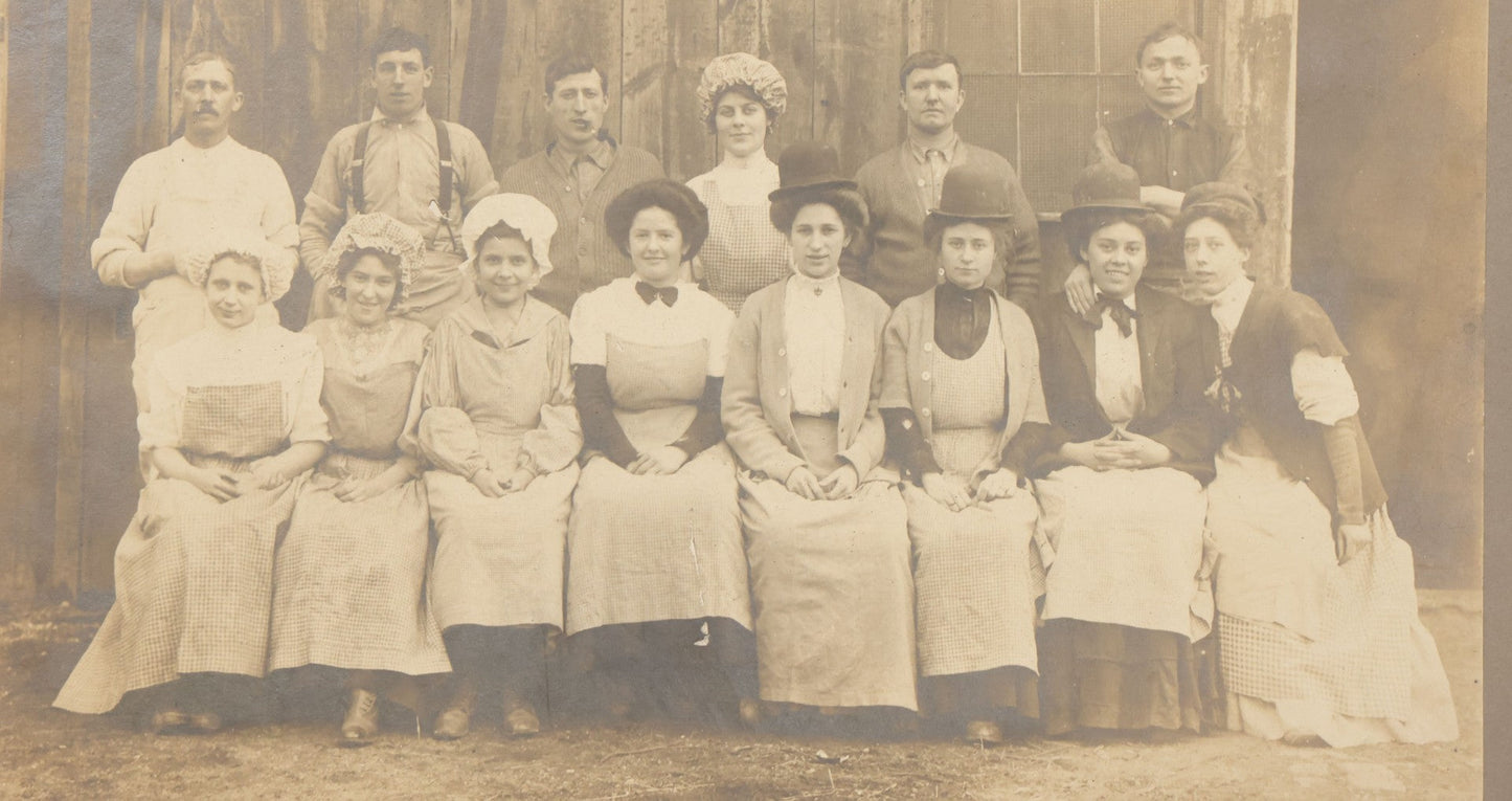 Lot 142 - Antique Boarded Occupational Photograph Of Men And Women Workers Posing In Workwear Outside A Barn, Women In Bowler Hats And Bonnets And Man Smoking Pipe
