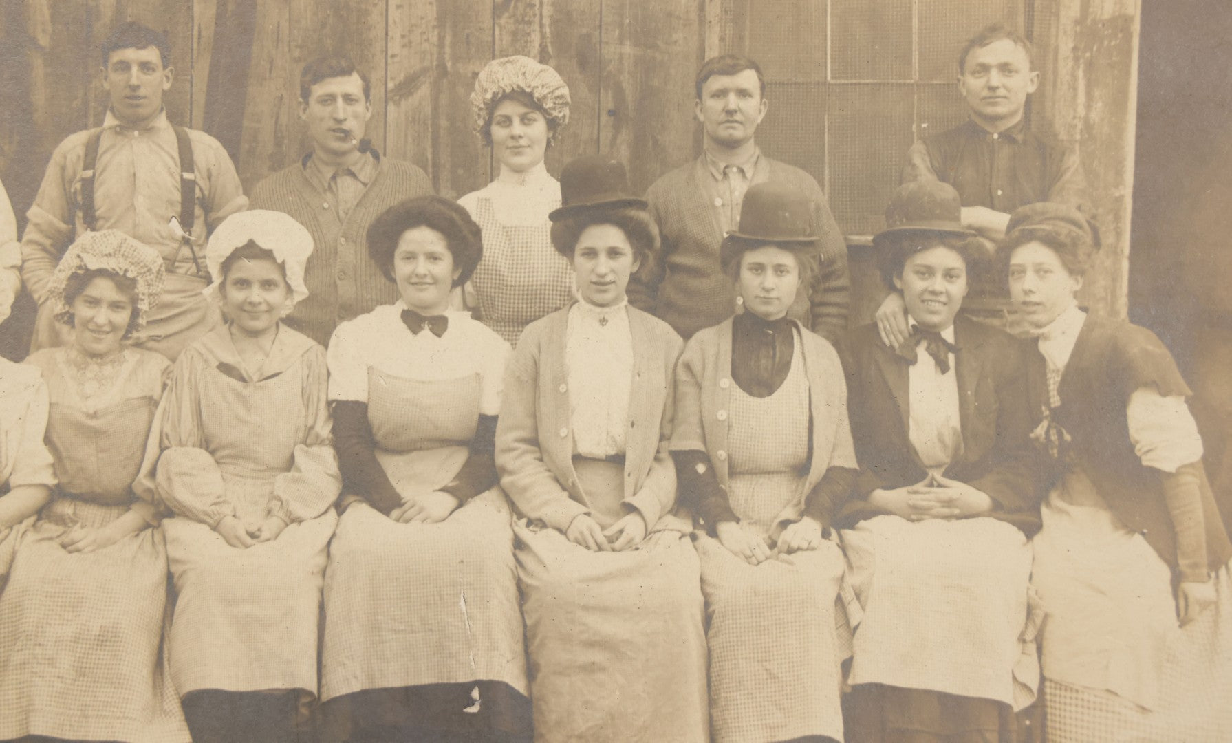 Lot 142 - Antique Boarded Occupational Photograph Of Men And Women Workers Posing In Workwear Outside A Barn, Women In Bowler Hats And Bonnets And Man Smoking Pipe