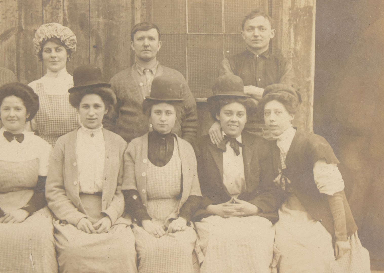 Lot 142 - Antique Boarded Occupational Photograph Of Men And Women Workers Posing In Workwear Outside A Barn, Women In Bowler Hats And Bonnets And Man Smoking Pipe