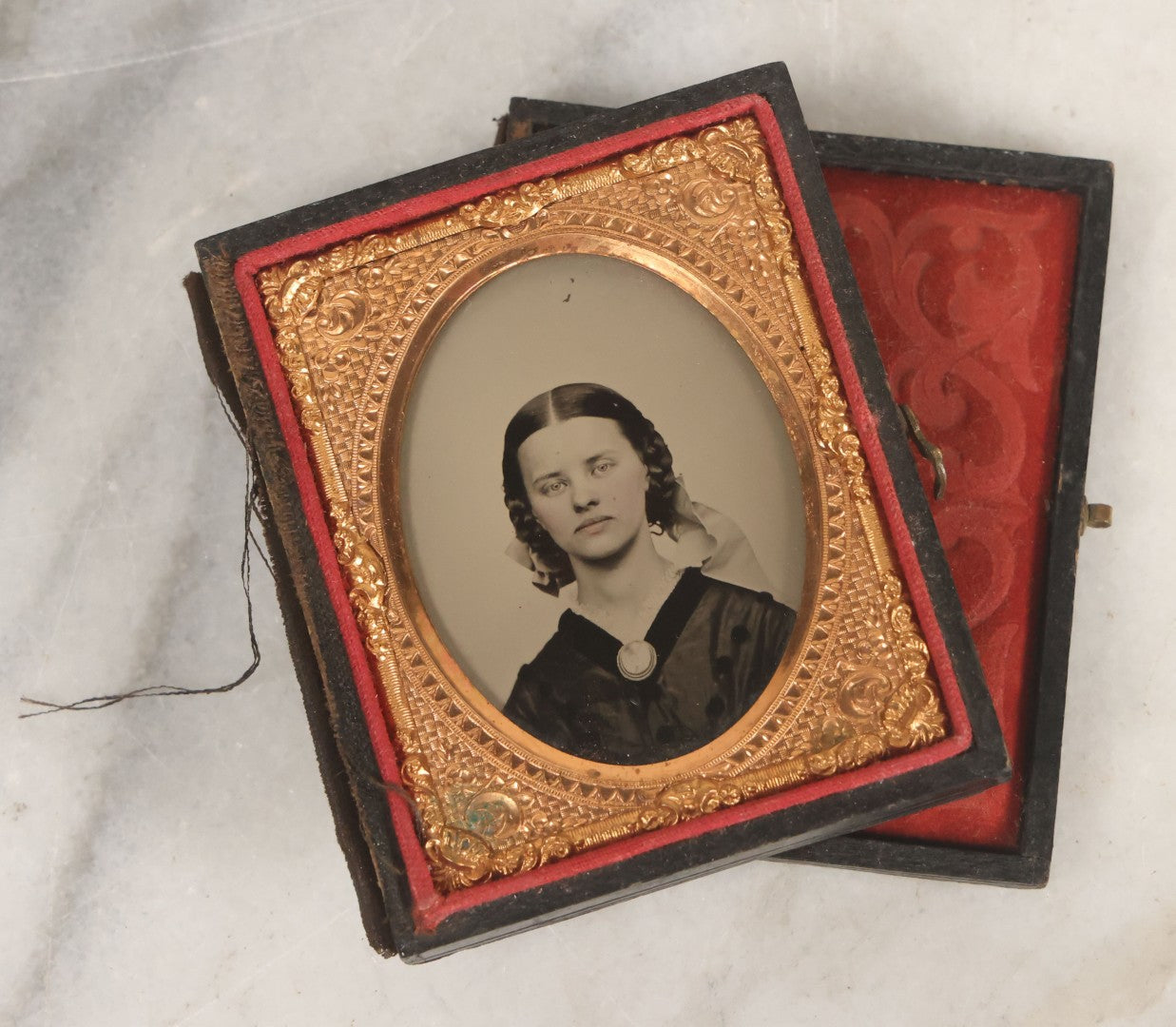 Lot 016 - Antique 1/9th Plate Ruby Ambrotype Photograph Of A Pretty Young Woman With Braided Hair, A Large Brooch, A Large Bow, And Tinted Lips, In Full Split Leatherette Union Case, C.F. Lamb, Photographer, Fitchburg, Massachusetts