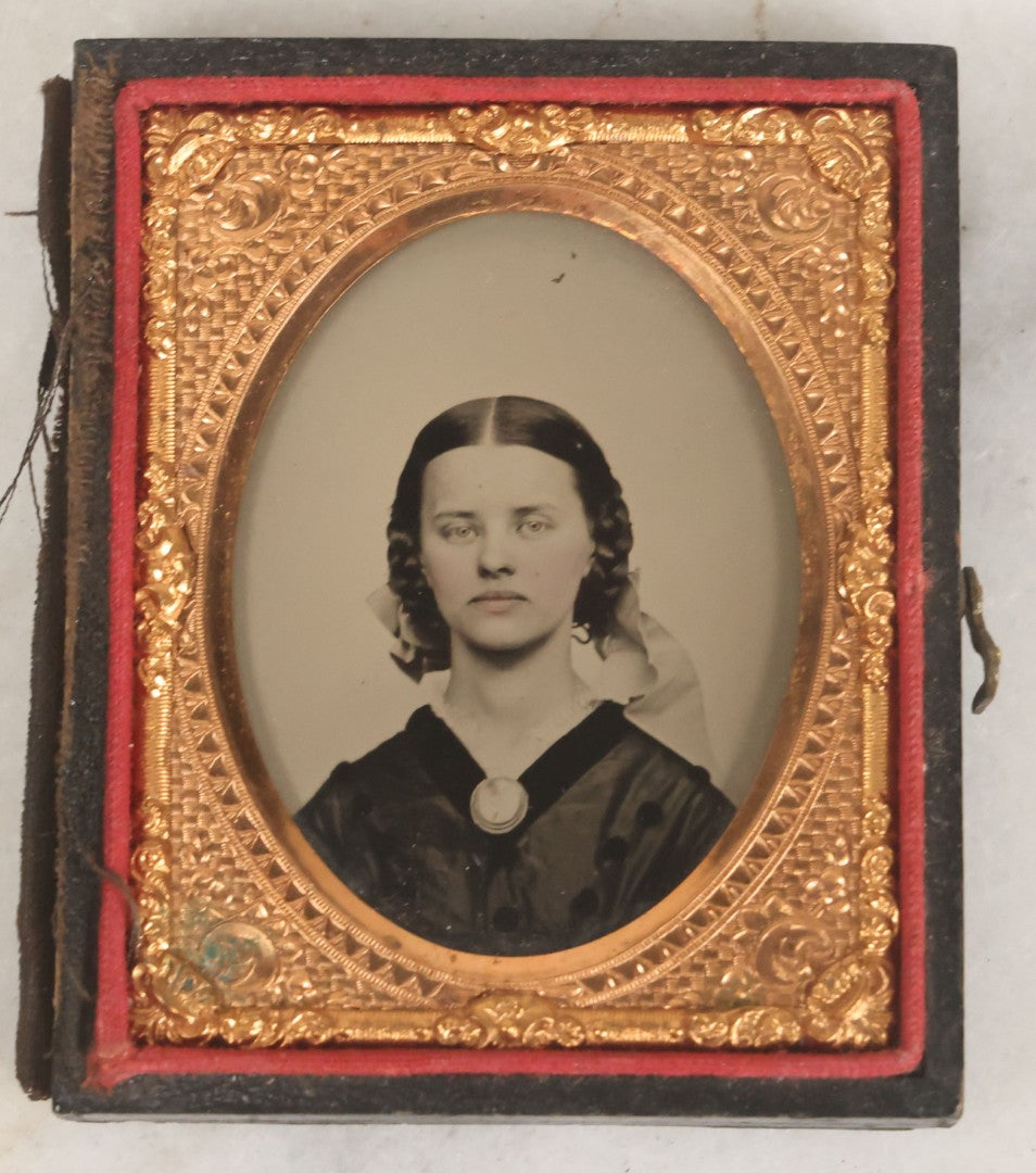 Lot 016 - Antique 1/9th Plate Ruby Ambrotype Photograph Of A Pretty Young Woman With Braided Hair, A Large Brooch, A Large Bow, And Tinted Lips, In Full Split Leatherette Union Case, C.F. Lamb, Photographer, Fitchburg, Massachusetts