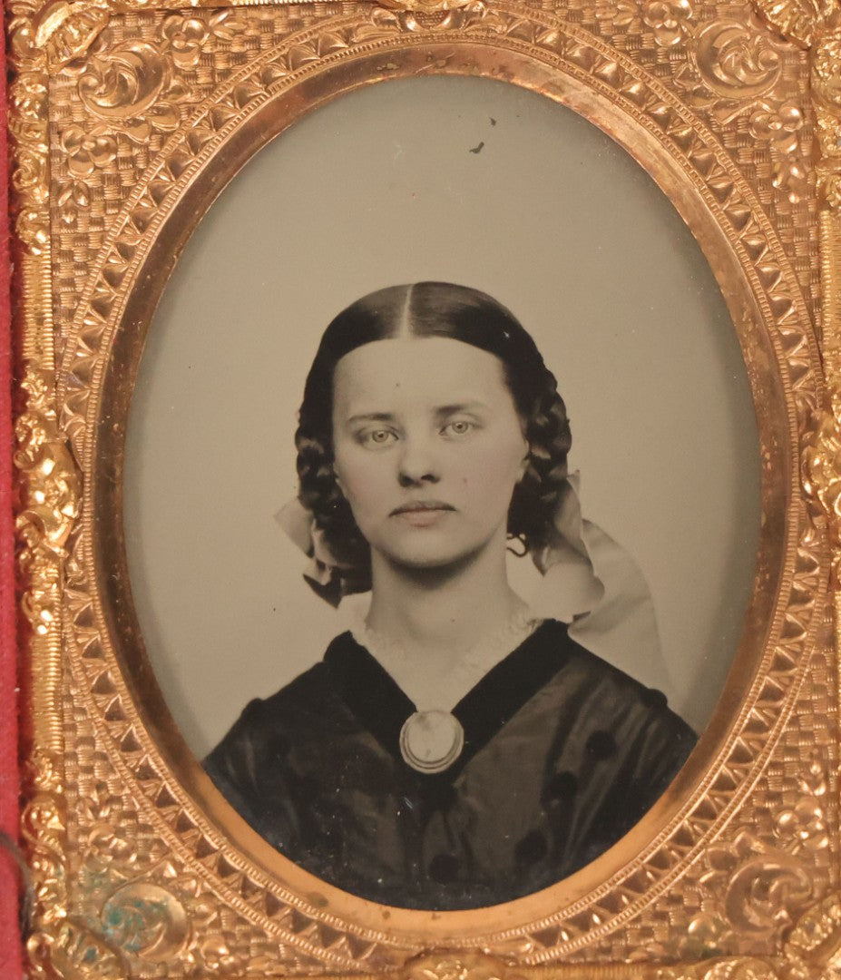 Lot 016 - Antique 1/9th Plate Ruby Ambrotype Photograph Of A Pretty Young Woman With Braided Hair, A Large Brooch, A Large Bow, And Tinted Lips, In Full Split Leatherette Union Case, C.F. Lamb, Photographer, Fitchburg, Massachusetts