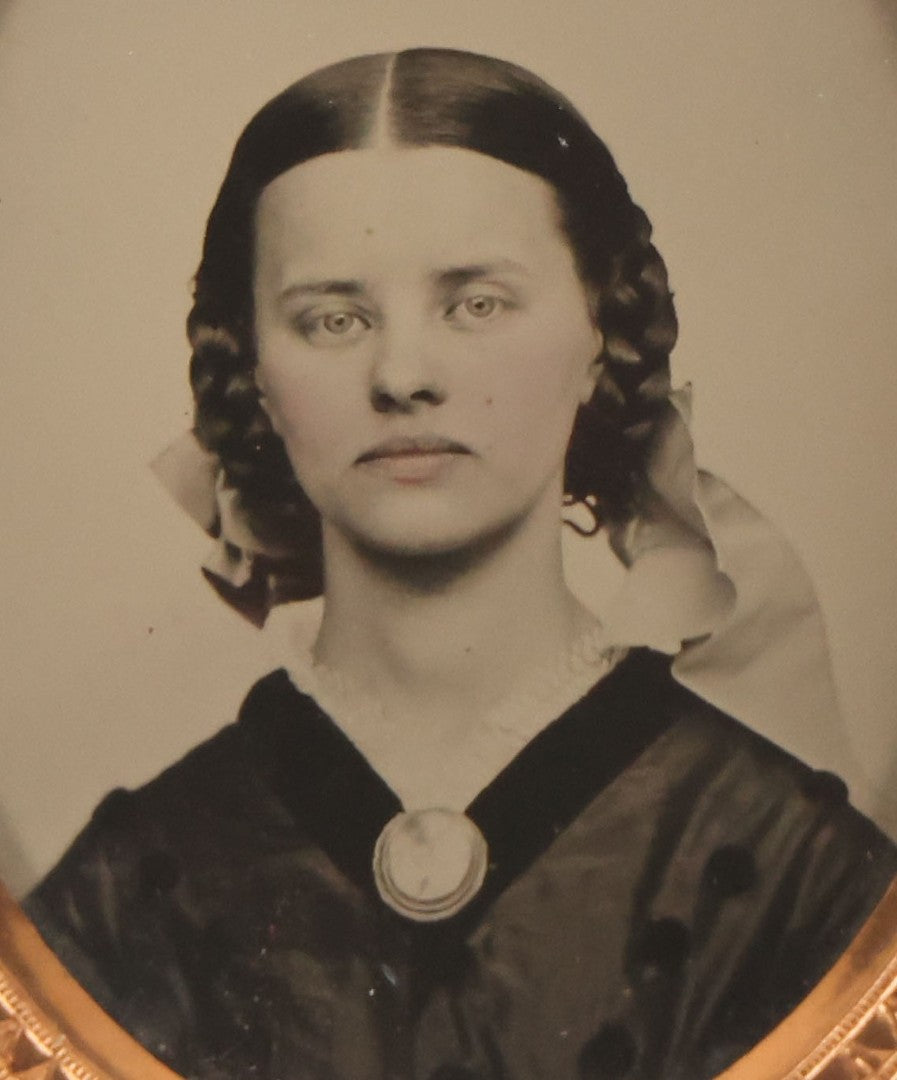 Lot 016 - Antique 1/9th Plate Ruby Ambrotype Photograph Of A Pretty Young Woman With Braided Hair, A Large Brooch, A Large Bow, And Tinted Lips, In Full Split Leatherette Union Case, C.F. Lamb, Photographer, Fitchburg, Massachusetts