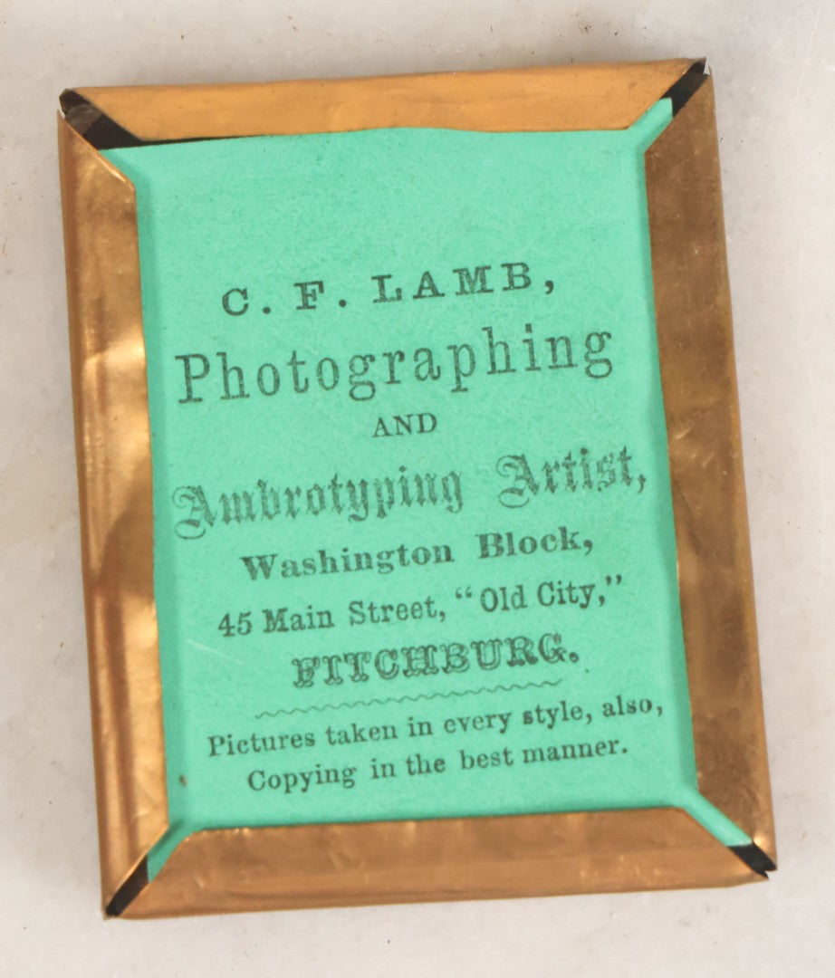 Lot 016 - Antique 1/9th Plate Ruby Ambrotype Photograph Of A Pretty Young Woman With Braided Hair, A Large Brooch, A Large Bow, And Tinted Lips, In Full Split Leatherette Union Case, C.F. Lamb, Photographer, Fitchburg, Massachusetts